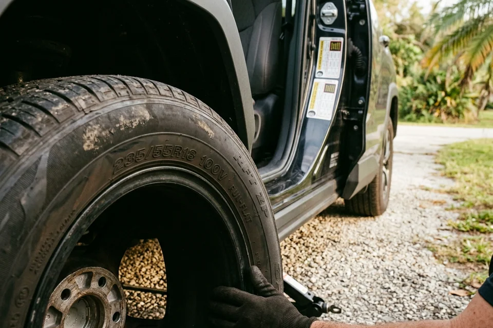 Close view of a tire sidewall showing the size string and a run-flat marking beside it, with the door placard visible in the open door behind
